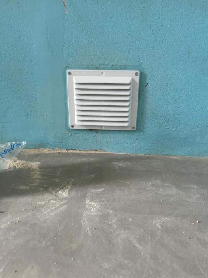 Grille de ventilation carrée en plastique blanc encastré dans un mur en béton Josselin