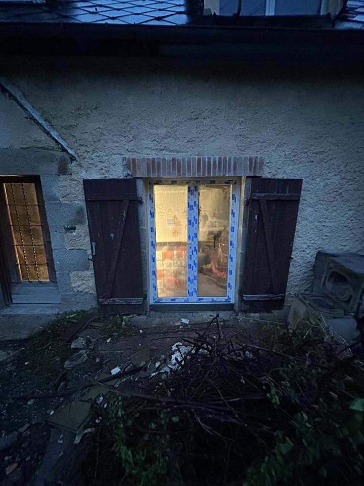 Fenêtre de sous-sol installée dans un mur en stuc ouvert Josselin