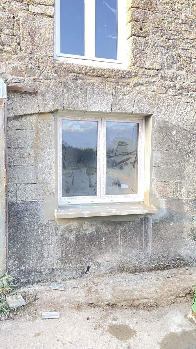 Fenêtre à double battant en PVC installée dans un mur de maçonnerie en pierre Josselin