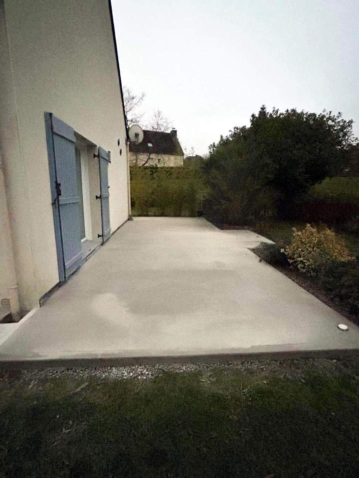 Terrasse extérieure en béton fraîchement coulée, prolongeant une maison Josselin